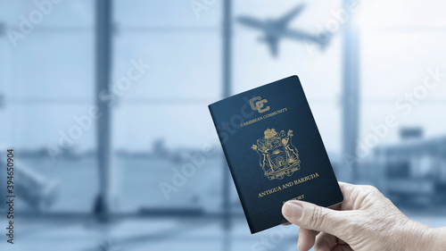 A hand holds a Antigua and Barbuda passport in the plane's waiting room photo
