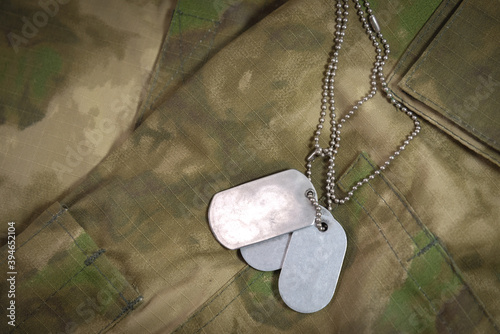Photography a soldier's badge with a chain lie on a military camouflage jacket