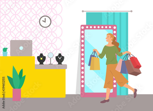 Smiling woman with shopping bags spend time in mall. Young beautiful happy girl with multi-colored packages. Female character with purchases choose necklace in jewelry store. Woman stands near mirror