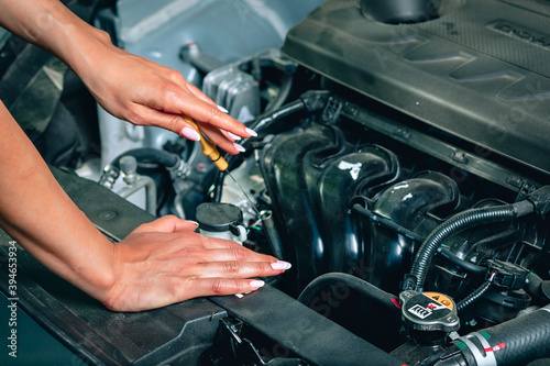 girl's soft and gentle hands are checking an oil in the car via an oil dipstick, close up
