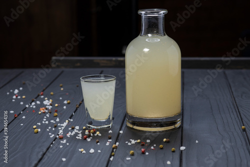Принти на полотні Bottle and glass of moonshine or vodka on black wooden table