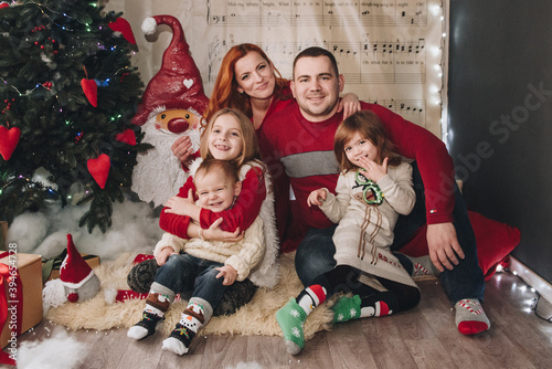 Two sisters and brother hug near the Christmas tree. Waiting for Santa Claus. open gifts. Big family.