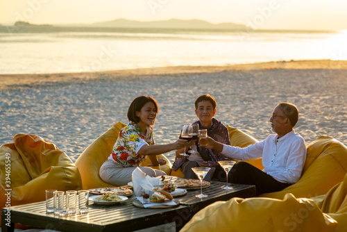 Group of Happy two generation Asian family enjoy dinner party together on the beach at sunset. Smiling senior parents with adult daughter relax and having fun together on summer holiday vacation © CandyRetriever 