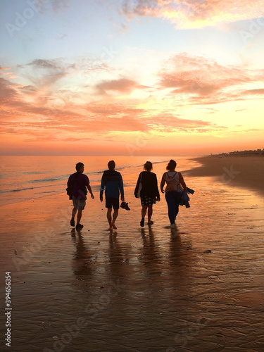 Group of friends walking at the beach during sunset