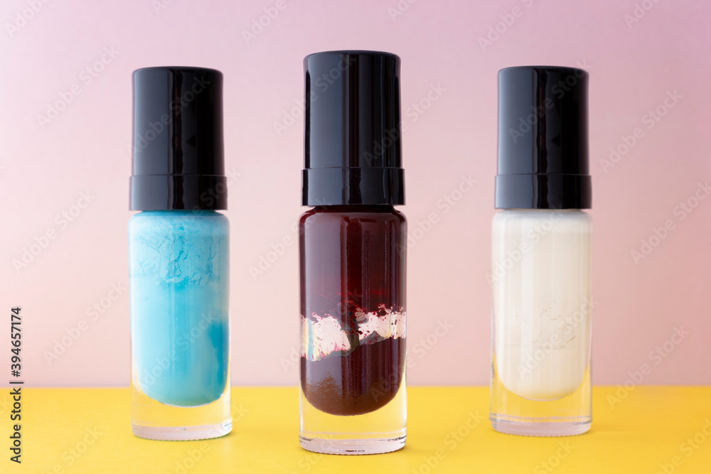 Different colors of aged and broken nail polish in selective focus. Old and dry nail varnish without labels. Hardened and dried finger nail polish bottles. PAO code and expired cosmetics concept. Different colors of aged and broken nail polish in selective focus. Old and dry nail varnish without labels. Hardened and dried finger nail polish bottles. PAO code and expired cosmetics concept.