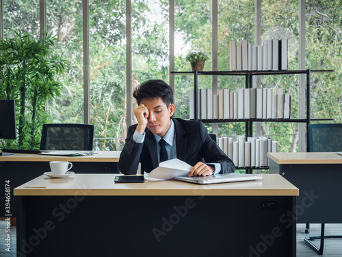 Stressed businessman. Young Asian business man in suit feeling down and tired.