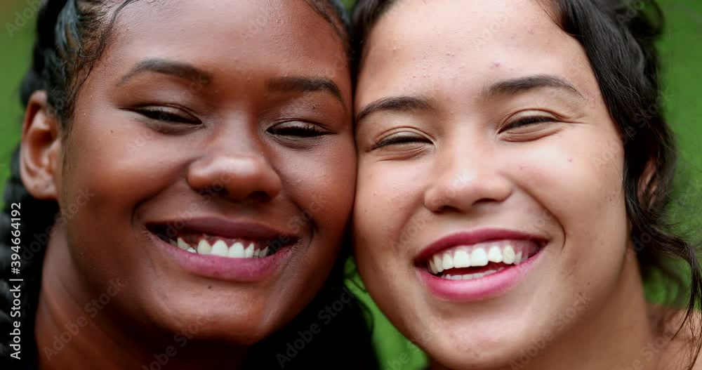 Girlfriends smiling, interracial mixed race friendship close-up faces smiling and laughing Girlfriends smiling, interracial mixed race friendship close-up faces smiling and laughing
