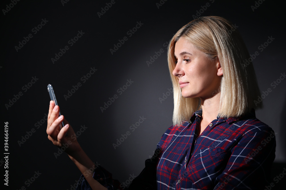 Woman using facial detection system of modern smartphone on dark background Woman using facial detection system of modern smartphone on dark background