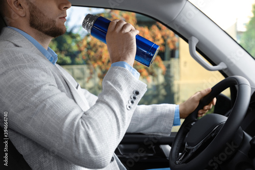 Man with thermos driving car, closeup view