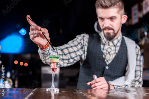 Professional barman demonstrates his skills over the counter at bar photo