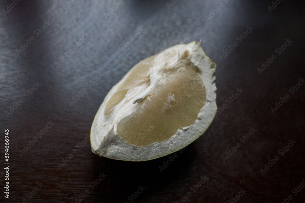a piece of pomelo fruit on a dark kitchen table