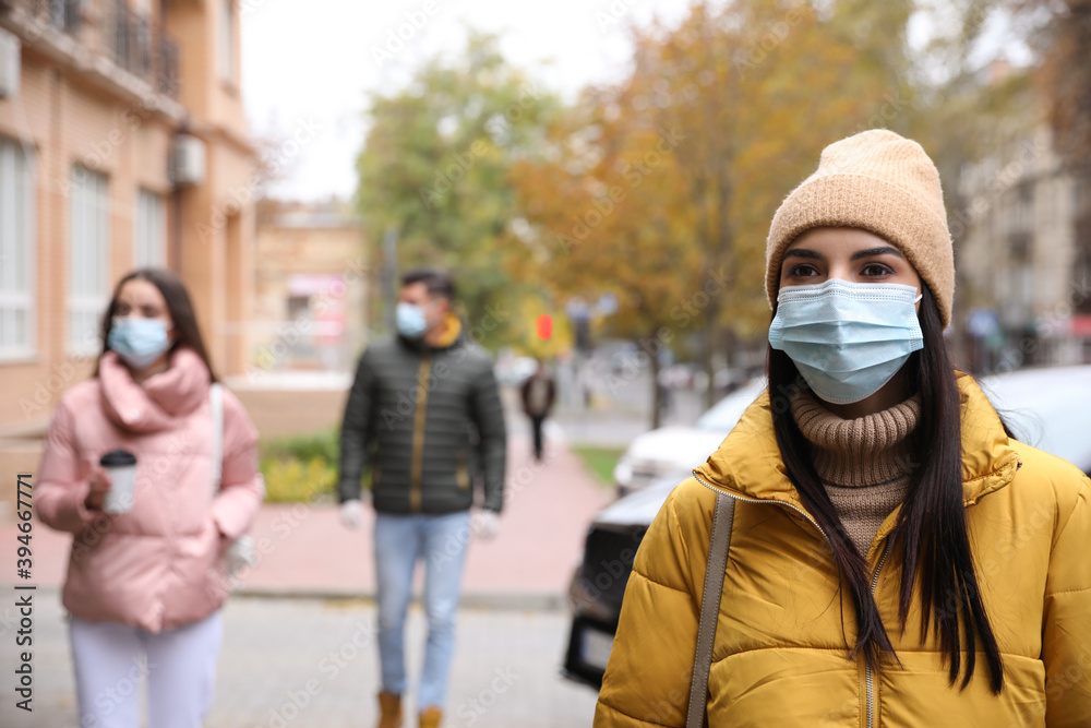 Young woman in medical face mask walking outdoors. Personal protection during COVID-19 pandemic Young woman in medical face mask walking outdoors. Personal protection during COVID-19 pandemic