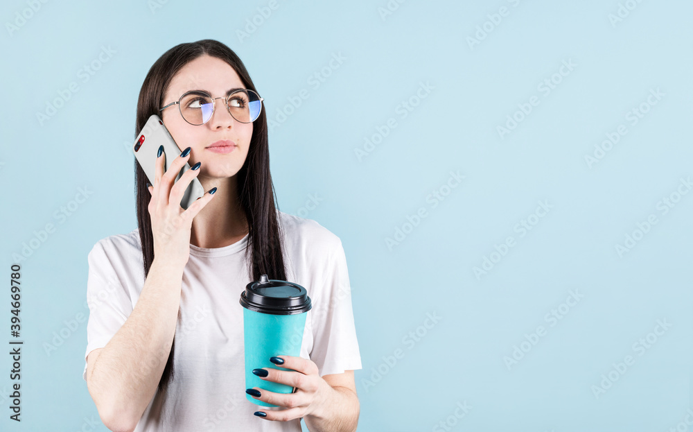 Image of happy american woman smiling and calling friend while drinking coffee isolated over blue wall with copyspace Image of happy american woman smiling and calling friend while drinking coffee isolated over blue wall with copyspace