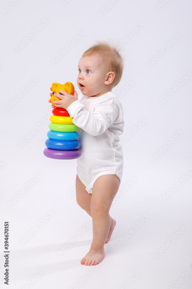 baby girl playing with colorful rainbow toy pyramid sitting on floor baby girl playing with colorful rainbow toy pyramid sitting on floor