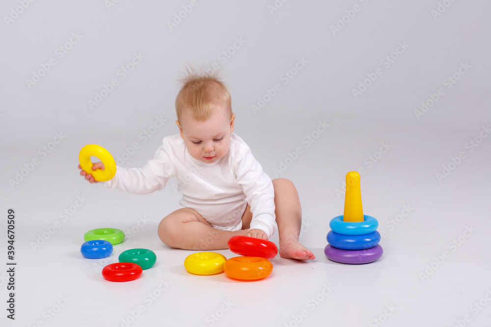 baby girl playing with colorful rainbow toy pyramid sitting on floor baby girl playing with colorful rainbow toy pyramid sitting on floor