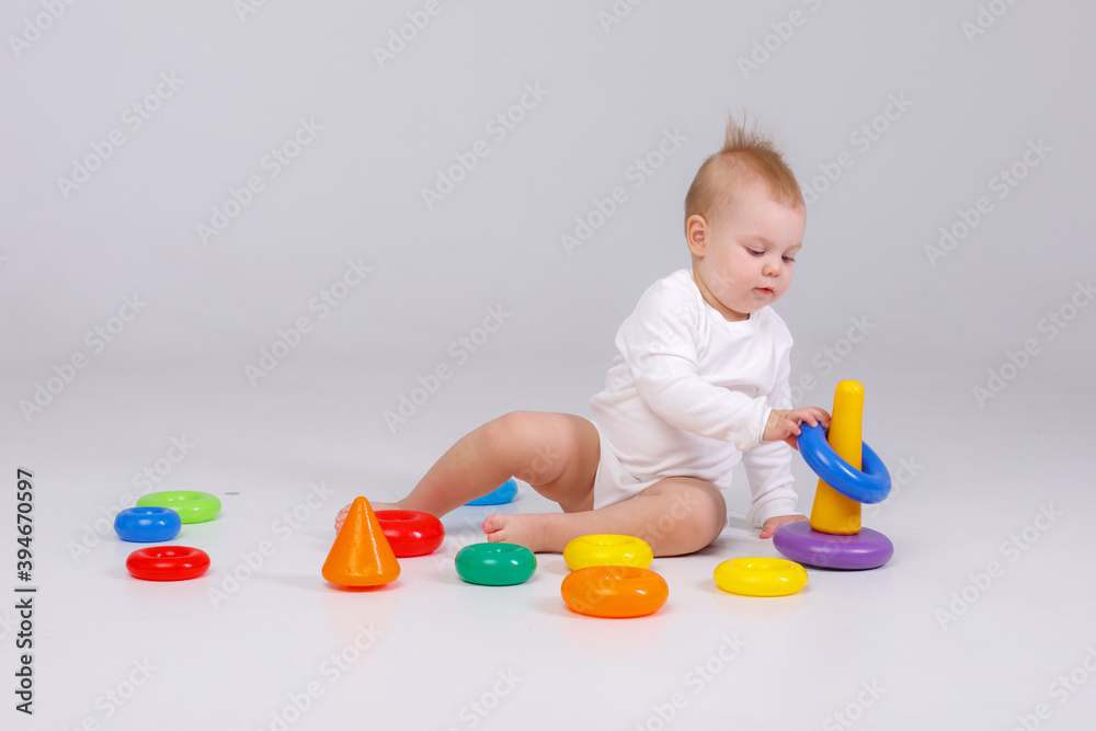 baby girl playing with colorful rainbow toy pyramid sitting on floor baby girl playing with colorful rainbow toy pyramid sitting on floor