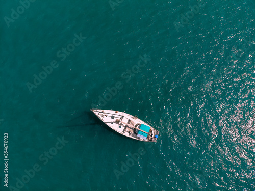 Aerial wonderful view of a enormous white and blue little boat sailing across the blue lagoona