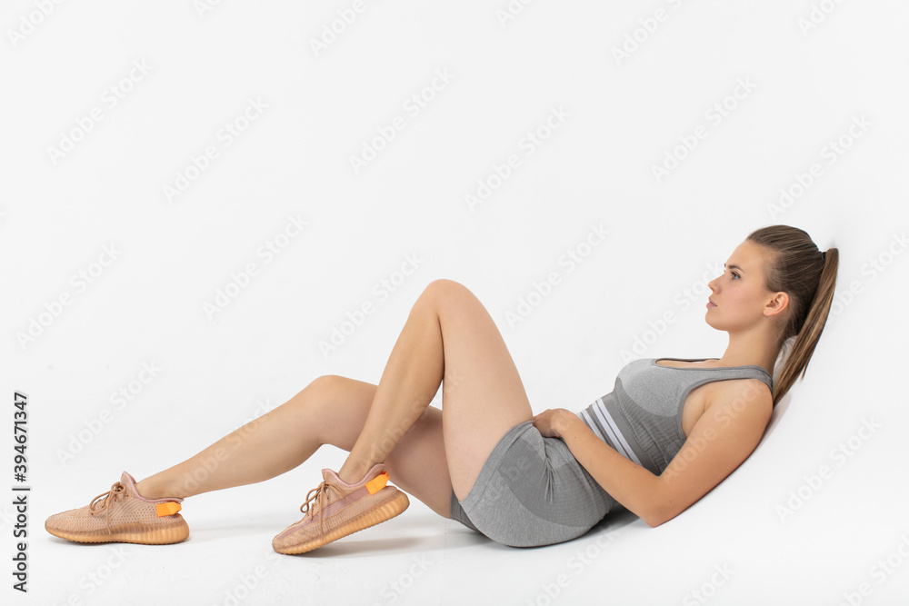 Young sporty woman in sportswear sitting and resting on white background. Young sporty woman in sportswear sitting and resting on white background.