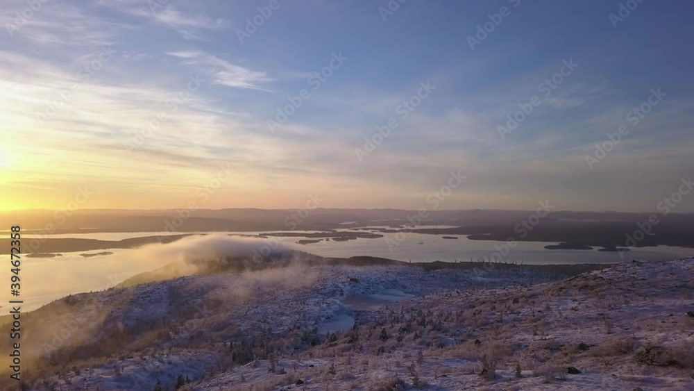 flying in a clear sky above low clouds over a snow-covered mountain illuminated by the rays of the sun flying in a clear sky above low clouds over a snow-covered mountain illuminated by the rays of the sun