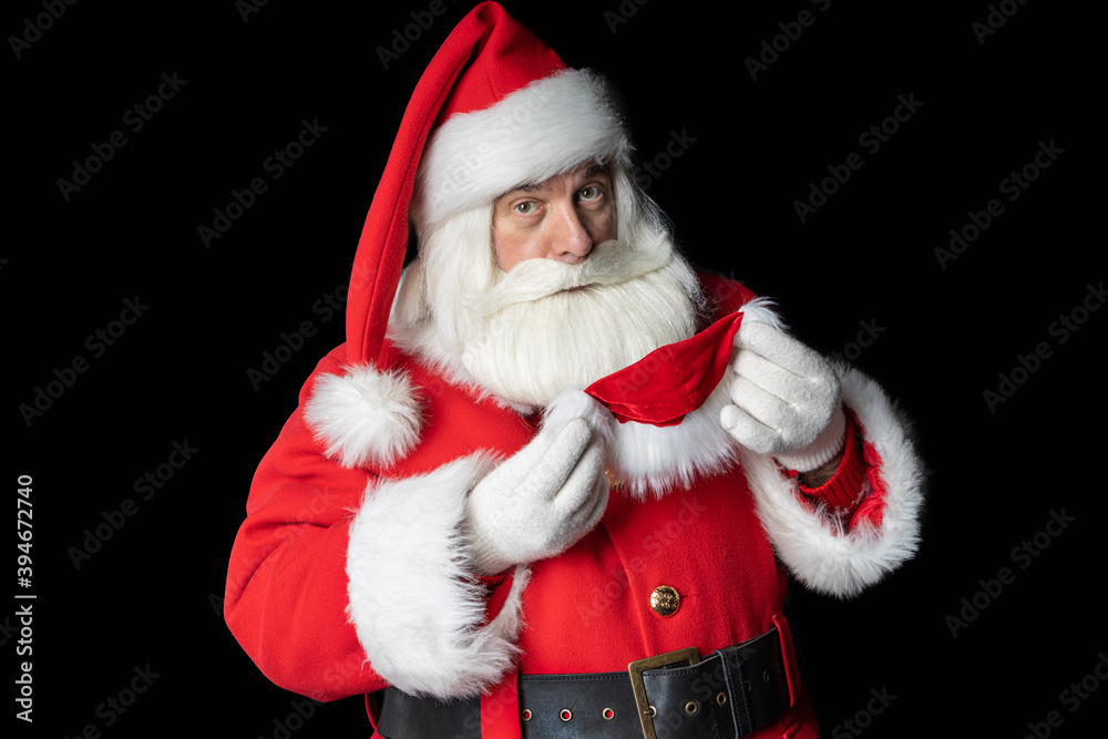 Santa Claus looks and tries on a mask. Black background. Santa Claus looks and tries on a mask. Black background.