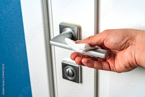 Hand wipes the door handle with an antibacterial disinfecting cloth, prevention of coronavirus
