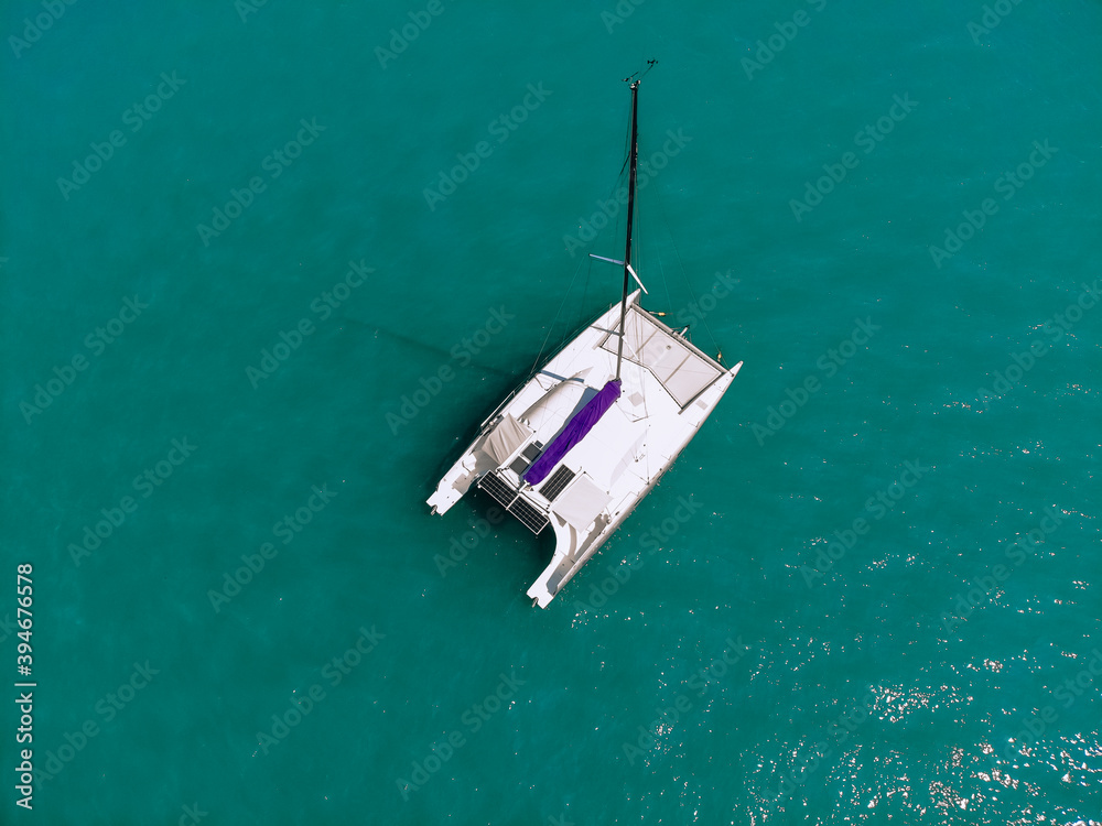 Picturesque top view of a huge white catamaran sailing across the deep sea. Aerial view.