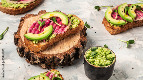 avocado and watermelon radish toasts on a light background, top view. Food recipe background. Close up