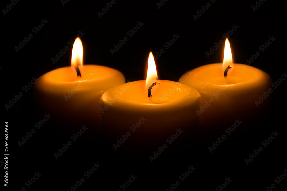 Three large white candles burn in the dark Three large white candles burn in the dark