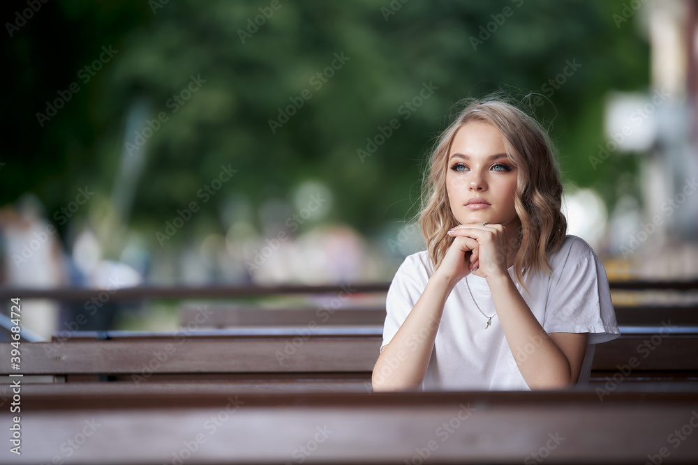 A beautiful woman looks thoughtfully into the distance while sitting in a summer cafe. A beautiful woman looks thoughtfully into the distance while sitting in a summer cafe.