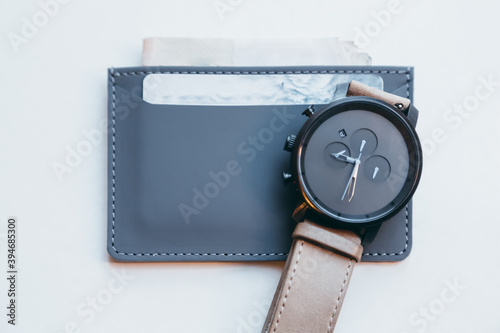 Close up photo of dark grey modern slim purse for credit cards and banknotes. Stylish handmade minimalistic accessories from eco leather. Smooth leather suture. Near classy hand watches. 