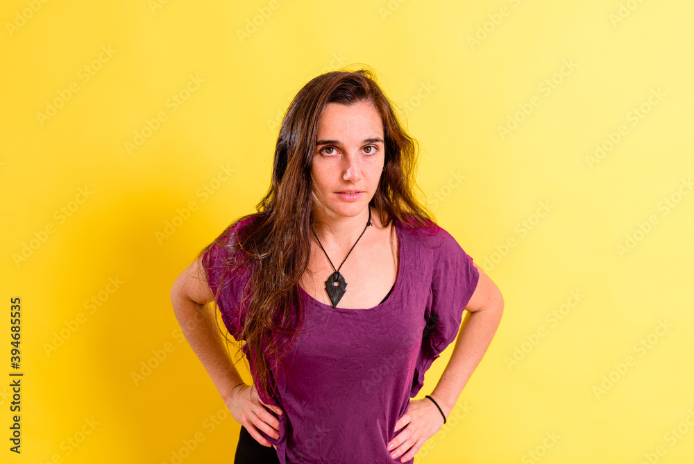 portrait of pretty 25 years old real girl without makeup posing looking at camera isolated on yellow studio background. portrait of pretty 25 years old real girl without makeup posing looking at camera isolated on yellow studio background.