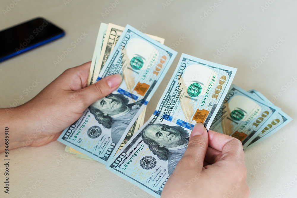 Woman's hands counting dollar bills, on white desk. Woman's hands counting dollar bills, on white desk.