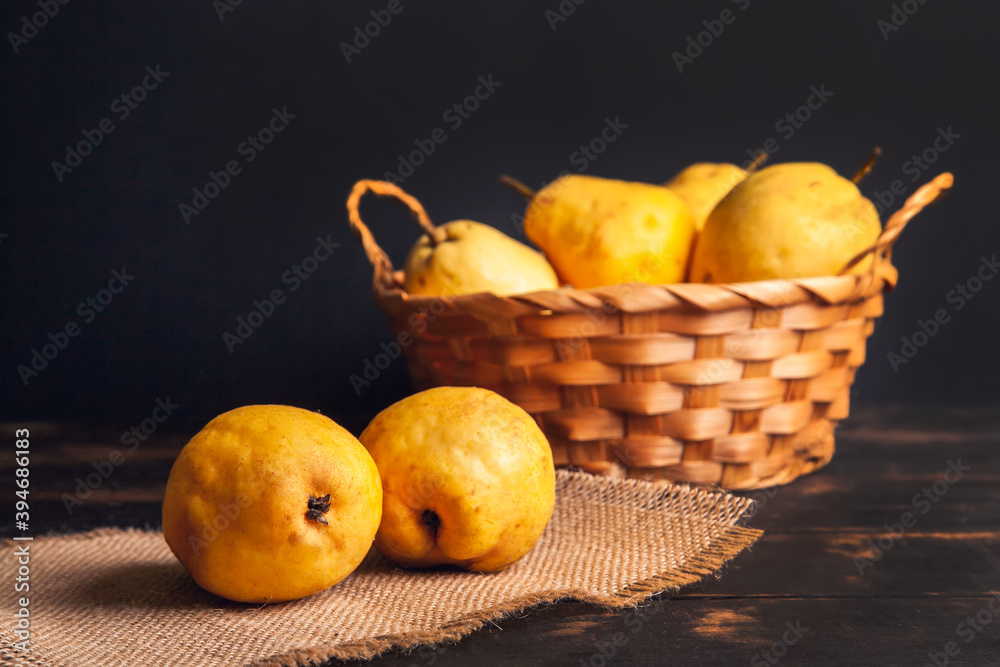 Natural pear fruit with defects in a basket on a jute napkin and a dark wooden background