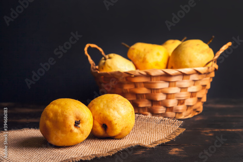 Natural pear fruit with defects in a basket on a jute napkin and a dark wooden background