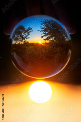 Rural landscape with trees at sunset seen through a crystal ball