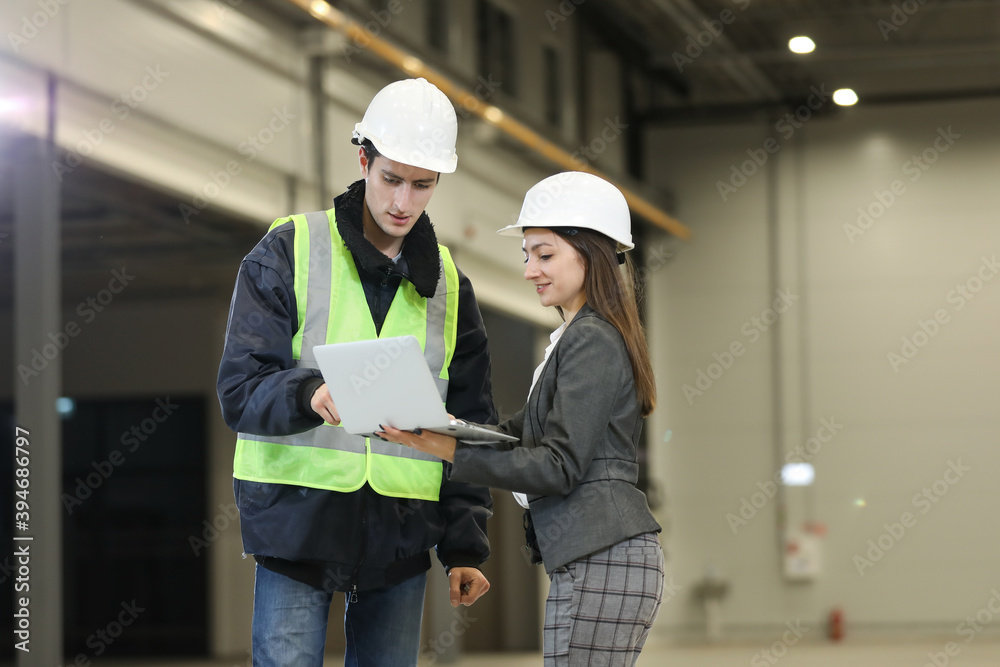 Portrait of a female factory manager in a white hard hat and business suit and factory engineer in work clothes. Controlling the work process in the helicopter manufacturer. Portrait of a female factory manager in a white hard hat and business suit and factory engineer in work clothes. Controlling the work process in the helicopter manufacturer.