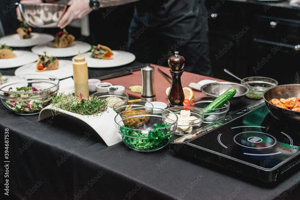 table with products for tacos. The chef at the restaurant is going to make Spicy Shrimp Tacos with Coleslaw and Salsa in front of the customers