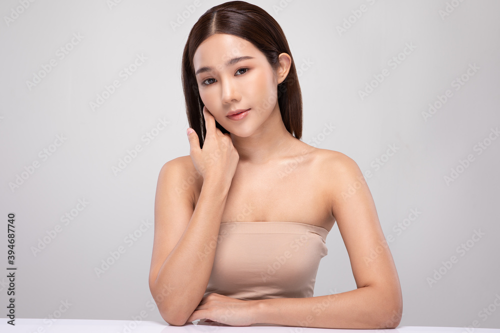 Obraz premium Beautiful Asian young woman touching soft cheek smile with clean and fresh skin Happiness and cheerful with positive emotional,isolated on gray background,Beauty and Cosmetics Concept