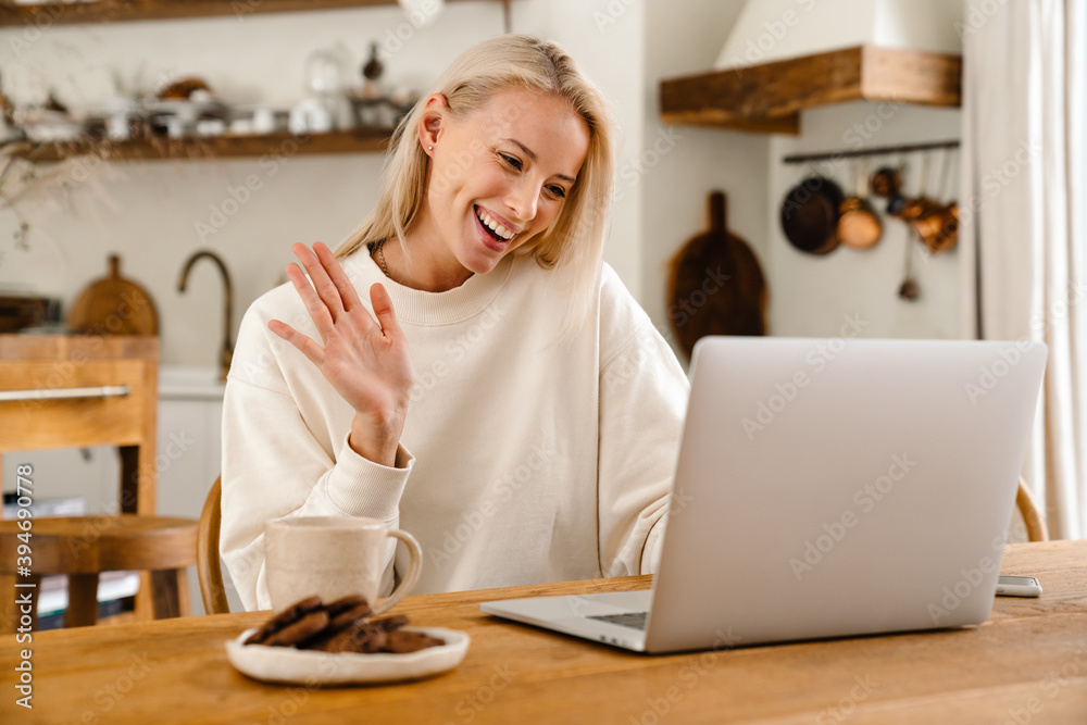 Beautiful joyful woman drinking tea while working with laptop Beautiful joyful woman drinking tea while working with laptop