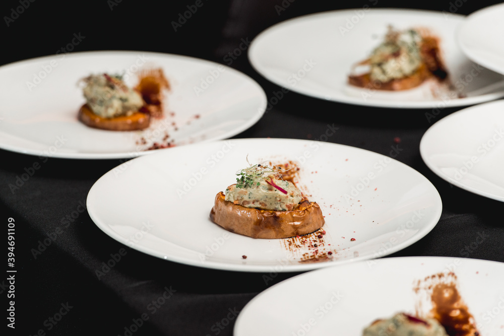 several white plates on a black table with baked sweet pumpkin and guacamole. Mexican cuisine at the restaurant