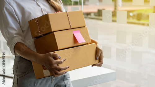 A young Asian woman shopping online starts a small business in a cardboard box at work. Seller provides shipping boxes for online sales customers. © ArLawKa