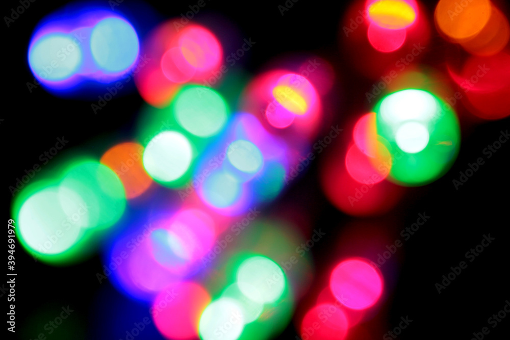 Christmas garland of electric multi-colored light bulbs. Abstract blurred background