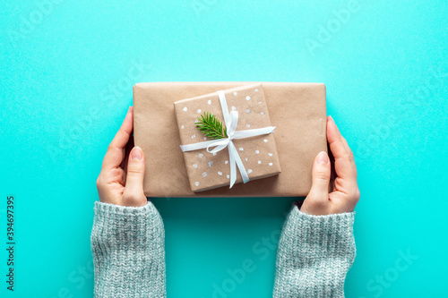 Female hands hold Christmas gifts in eco wrapping paper on azure background