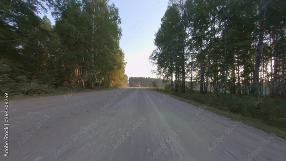 The road is going through the natural landscape, forests and fields stretch on both sides. View from a car driving down a road. Road surrounded by forest and then field. The road is going through the natural landscape, forests and fields stretch on both sides. View from a car driving down a road. Road surrounded by forest and then field.