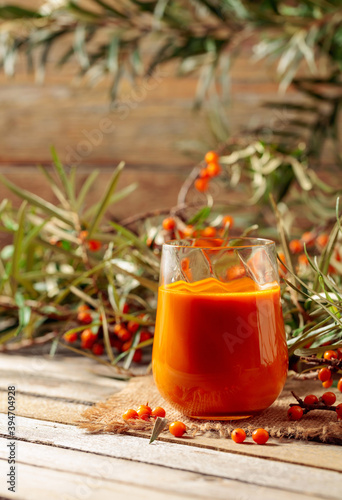 A glass of sea buckthorn juice with fresh berries on an old wooden table. Healthy and diet food.