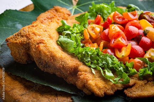 Vászonkép Veal milanese (cotoletta alla milanese) with fresh vegetable and tomatoes, salad close-up on a plate