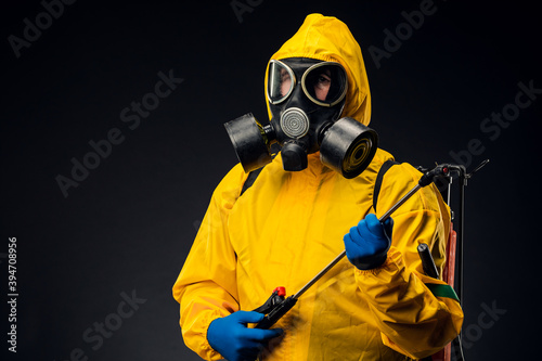 Fotografi Portrait of a man in a yellow chemical protection suit holding a sprayed disinfe