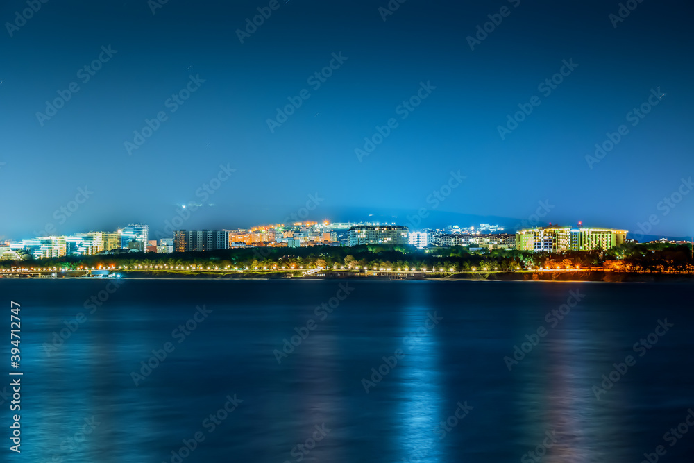 Night view of illuminated embankment of small resort town Gelendzhik from other side of bay at night.
