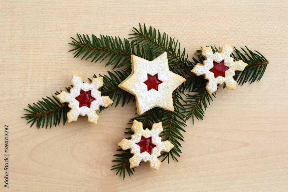 Fototapeta premium Homemade linzer cookies in a shape of snowflakes and star filled with strawberry jam on a spruce twig