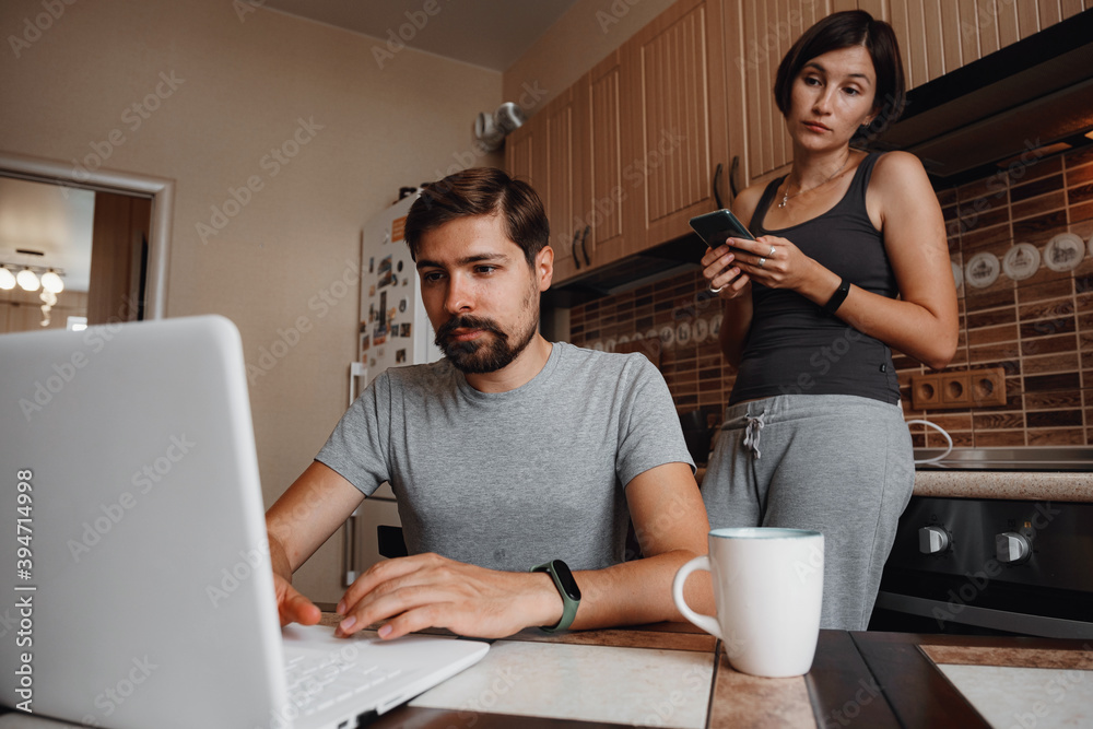 Couple at kitchen, reading news and using laptop. Couple at kitchen, reading news and using laptop.